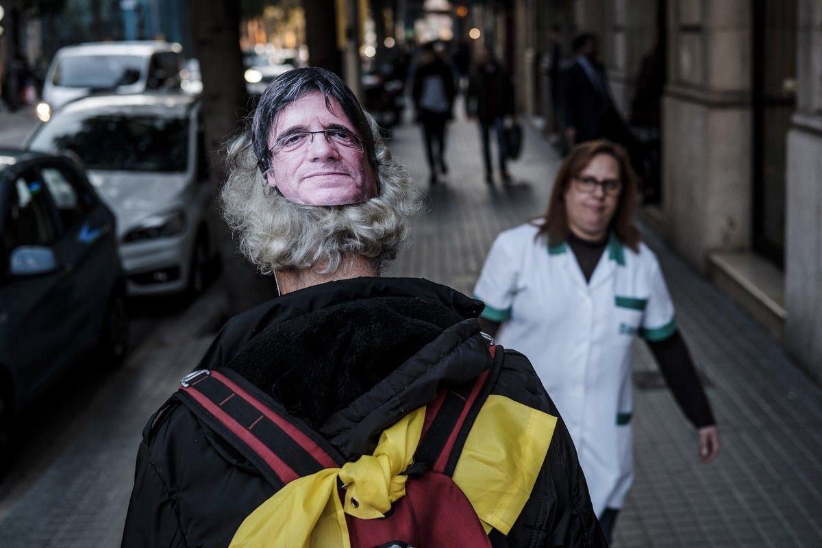 Un ciutadà passeja amb una careta de Puigdemont pels carrers de Barcelona