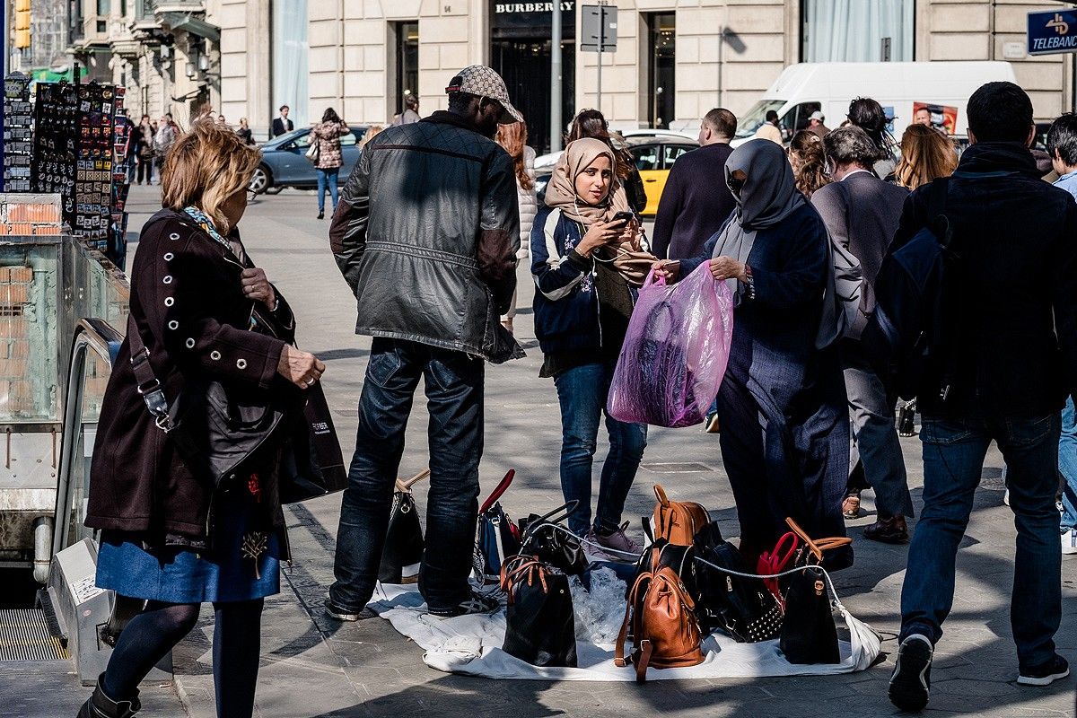 Unes turistes compant un bolso a un manter del passeig de Gràcia.