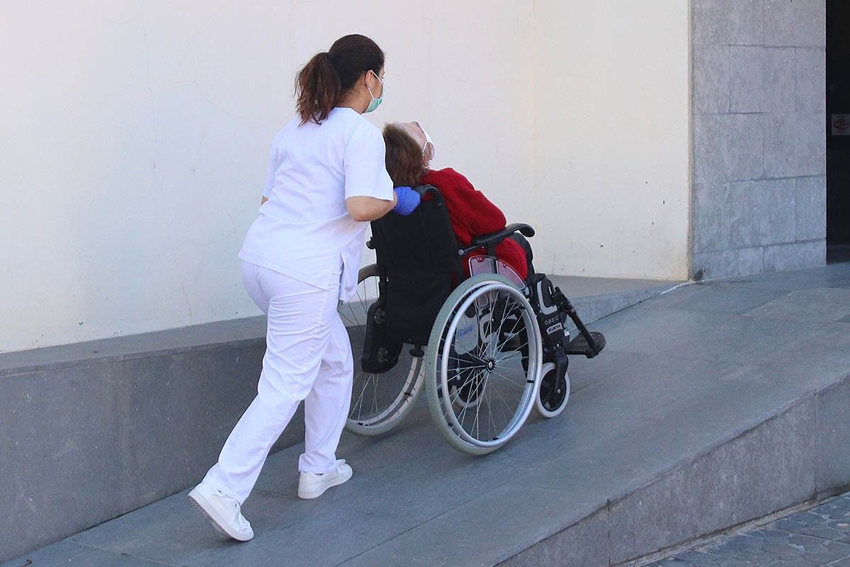Personal sanitari traslladant una persona gran en cadira de rodes