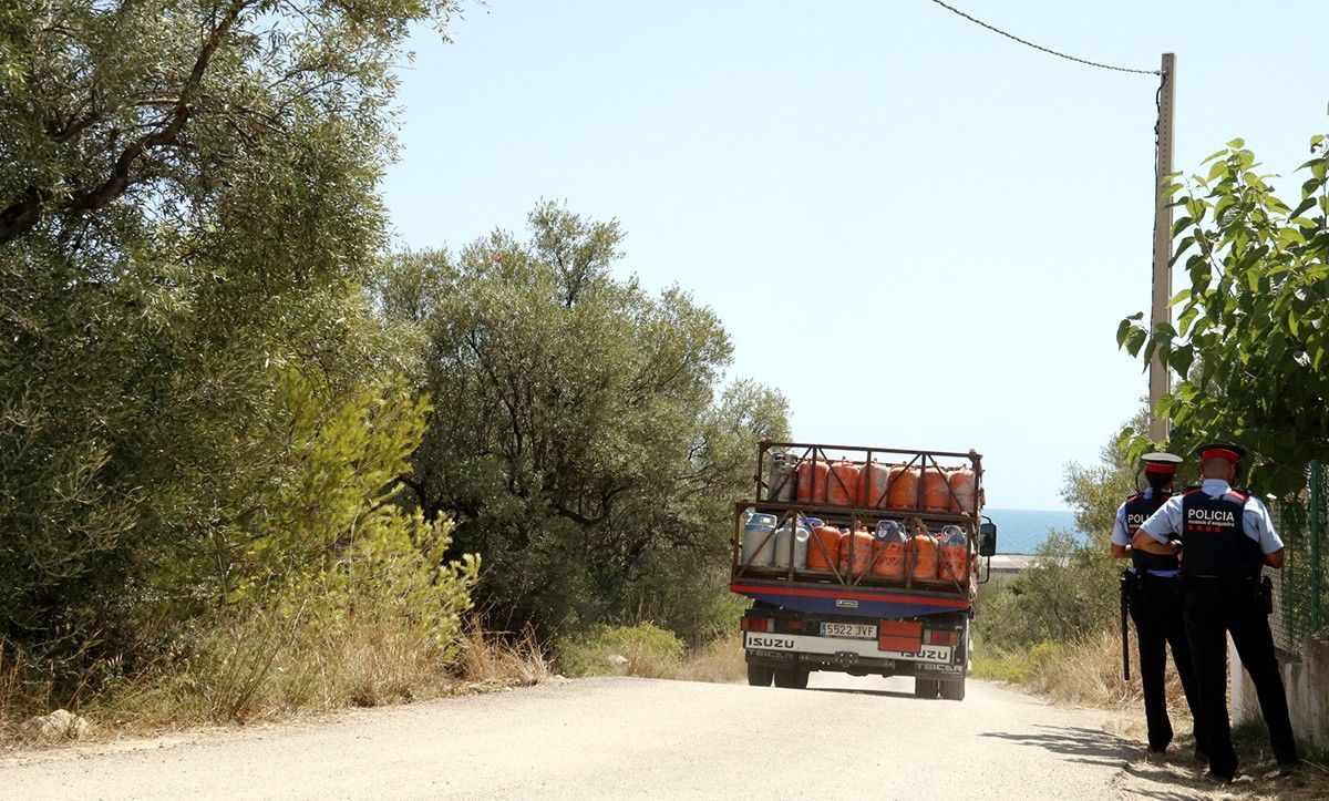 Pla obert del camió carregat de bombones de butà sortint de la urbanització Montecarlo d'Alcanar amb una patrulla de Mossos mirant-s'ho.