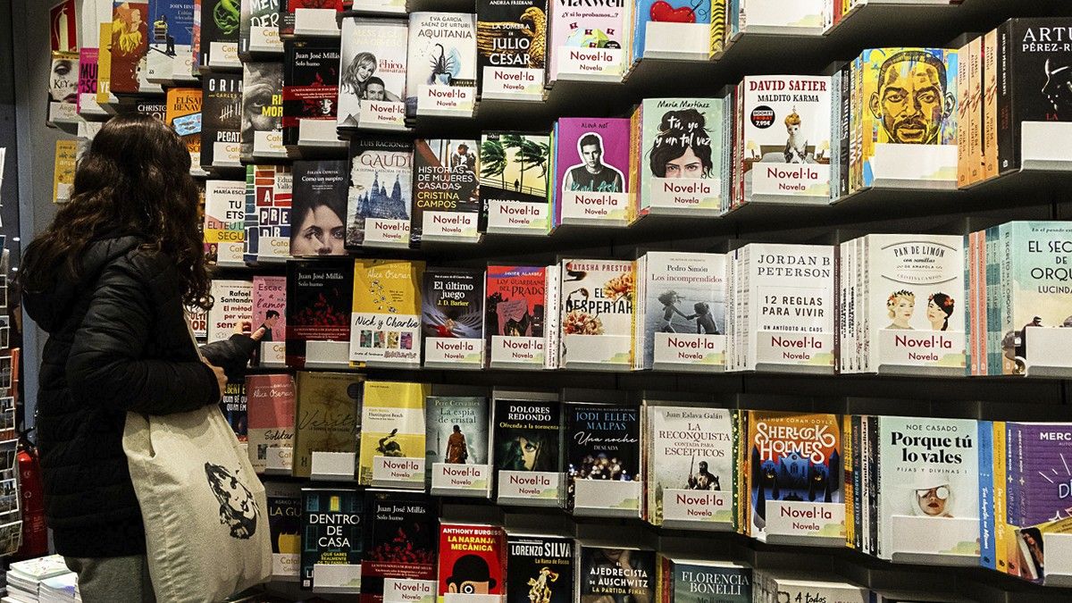 Una noia agafa un llibre en català a la botiga Divers de l'estació de Sants