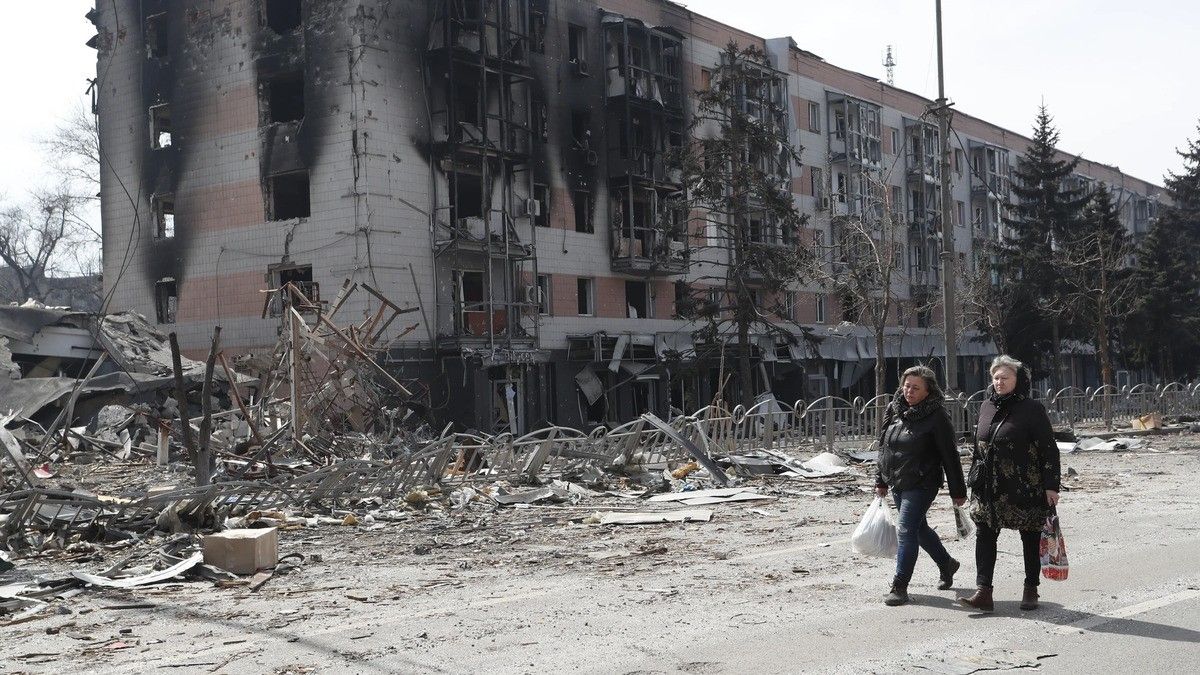 Dues dones passejant per Mariupol en una estranya normalitat després d'un bombardeig rus.