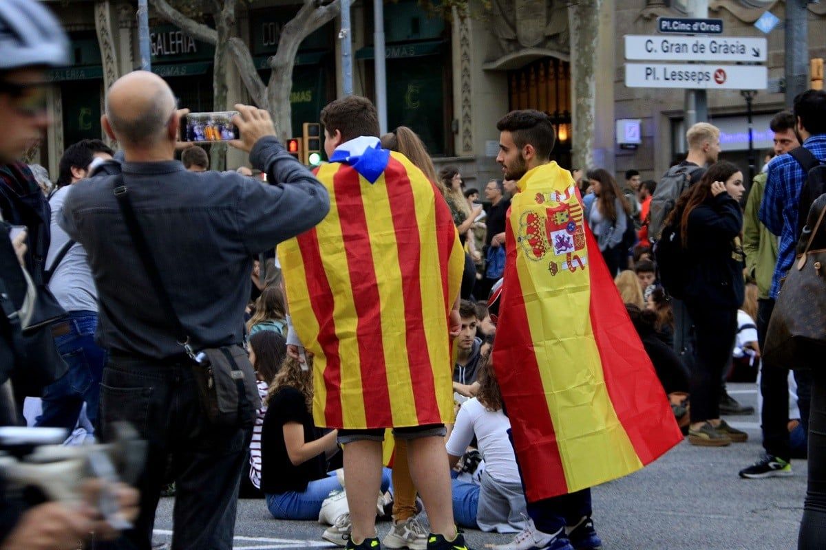 Dos nois porten una bandera estelada i una d'espanyola a una concentració.
