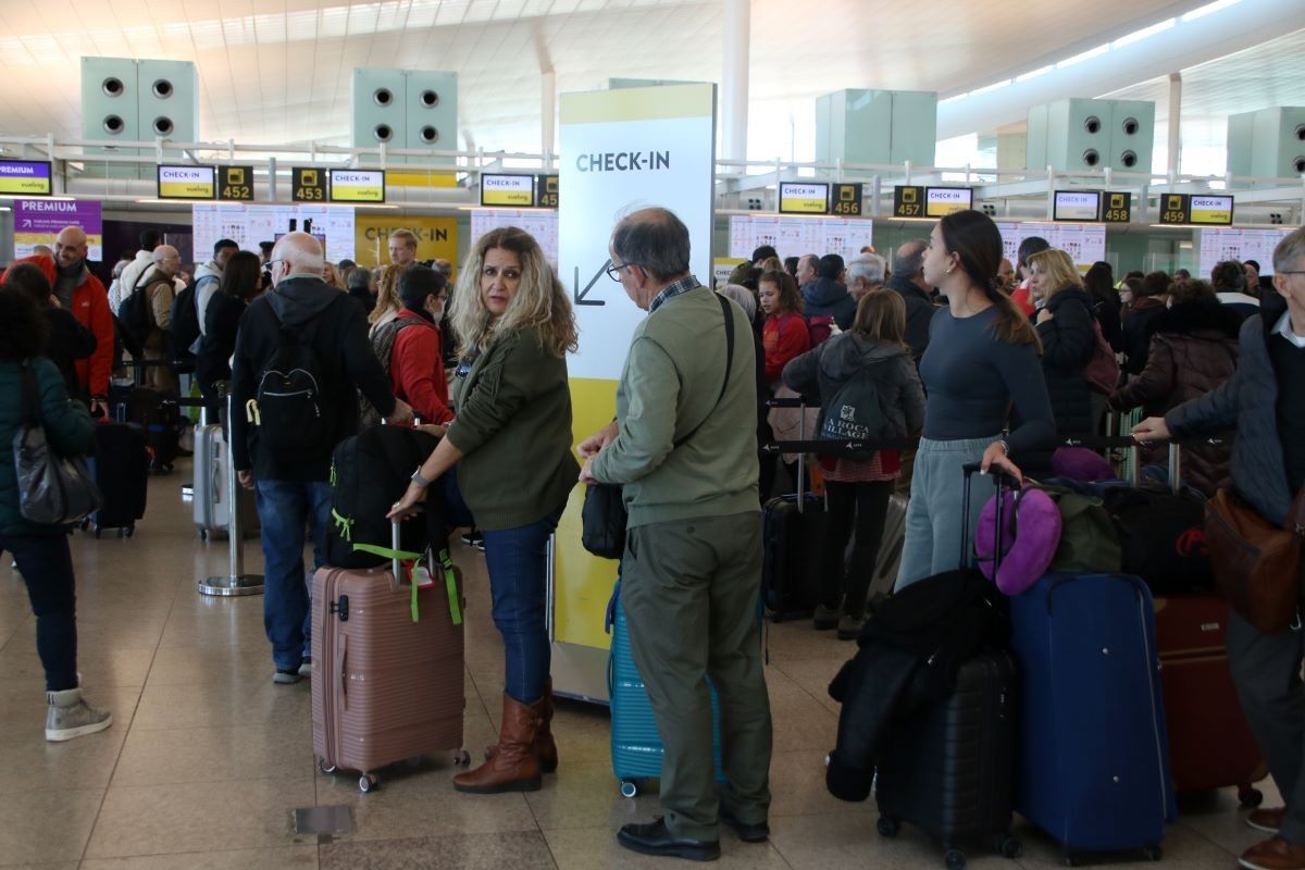 Passatgers de Vueling fan cua abans de facturar les maletes, a l'aeroport del Prat