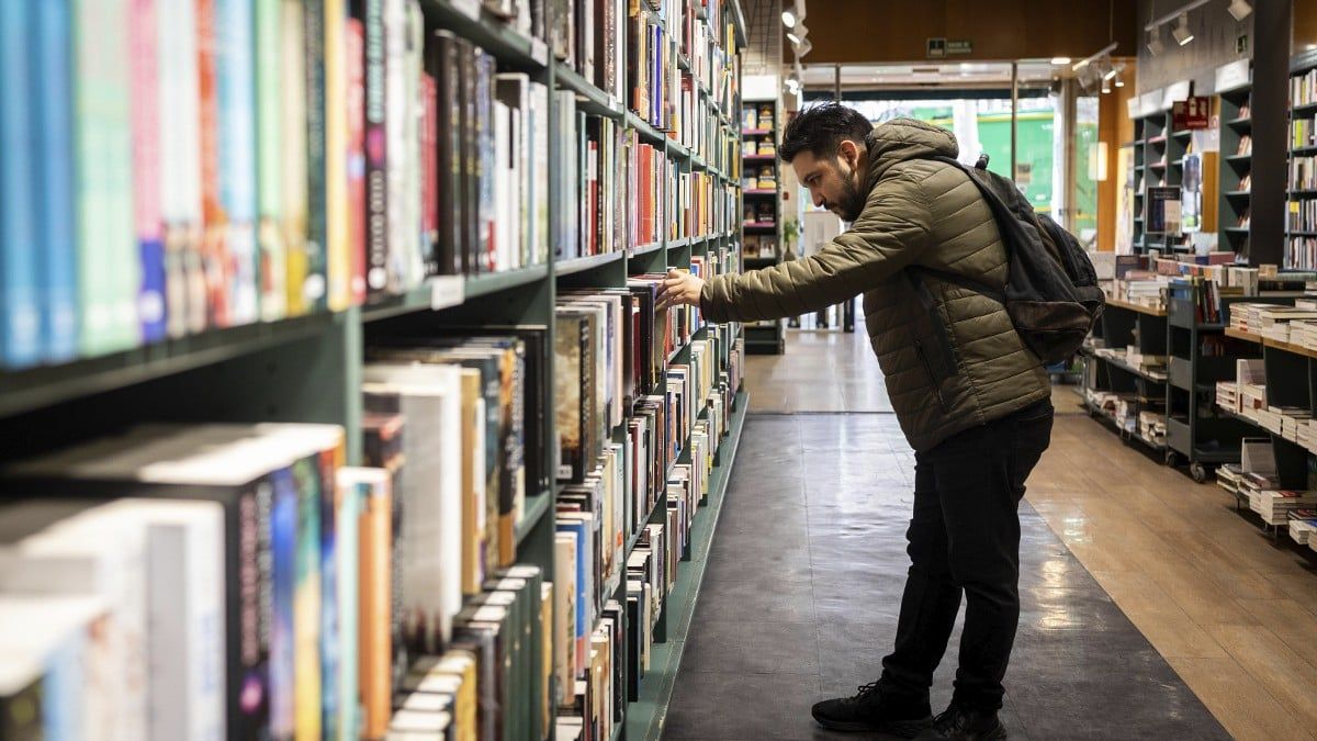 Un jove tria un llibre en una llibreria de Barcelona